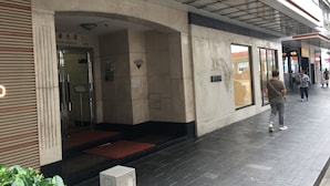 A building entrance with a glass door, a red carpet, and a sign above the door. - Seasons Hotel - Causeway Bay (Hong Kong)