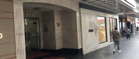 Entrada de un edificio con puerta de cristal, alfombra roja y un letrero sobre la puerta.