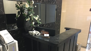 A reception desk with a telephone, a small sign, and a vase with flowers. - Seasons Hotel - Causeway Bay (Hong Kong)