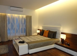 A modern hotel room with a large bed, two bedside lamps, and a window with curtains.