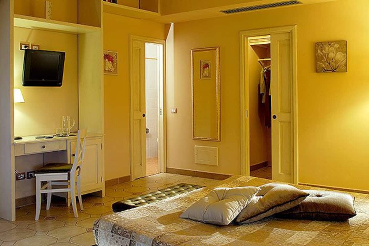 Una habitación de hotel con una cama, un escritorio, una silla, un televisor y un armario.