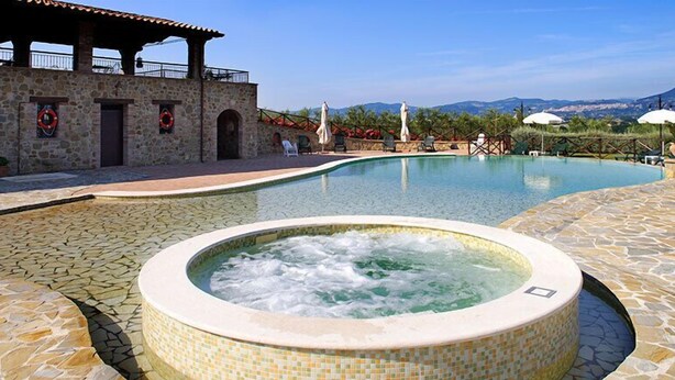 Ein Pool mit Whirlpool, Steinwänden und Sitzgelegenheiten im Freien.