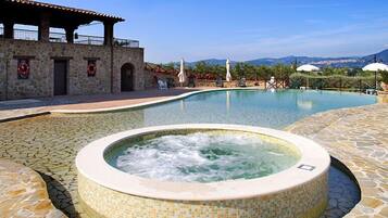 Relax by the serene pool, featuring a hot tub and stone-tiled deck, with a mountain view.