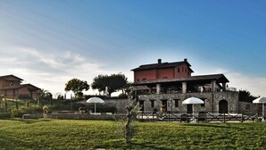Ein historisches Gebäude mit einer Steinfassade, einem roten Dach und einem Balkon mit Blick auf einen angelegten Garten.