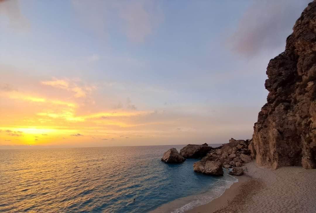 A coastal landscape with a rocky cliff and a beach.