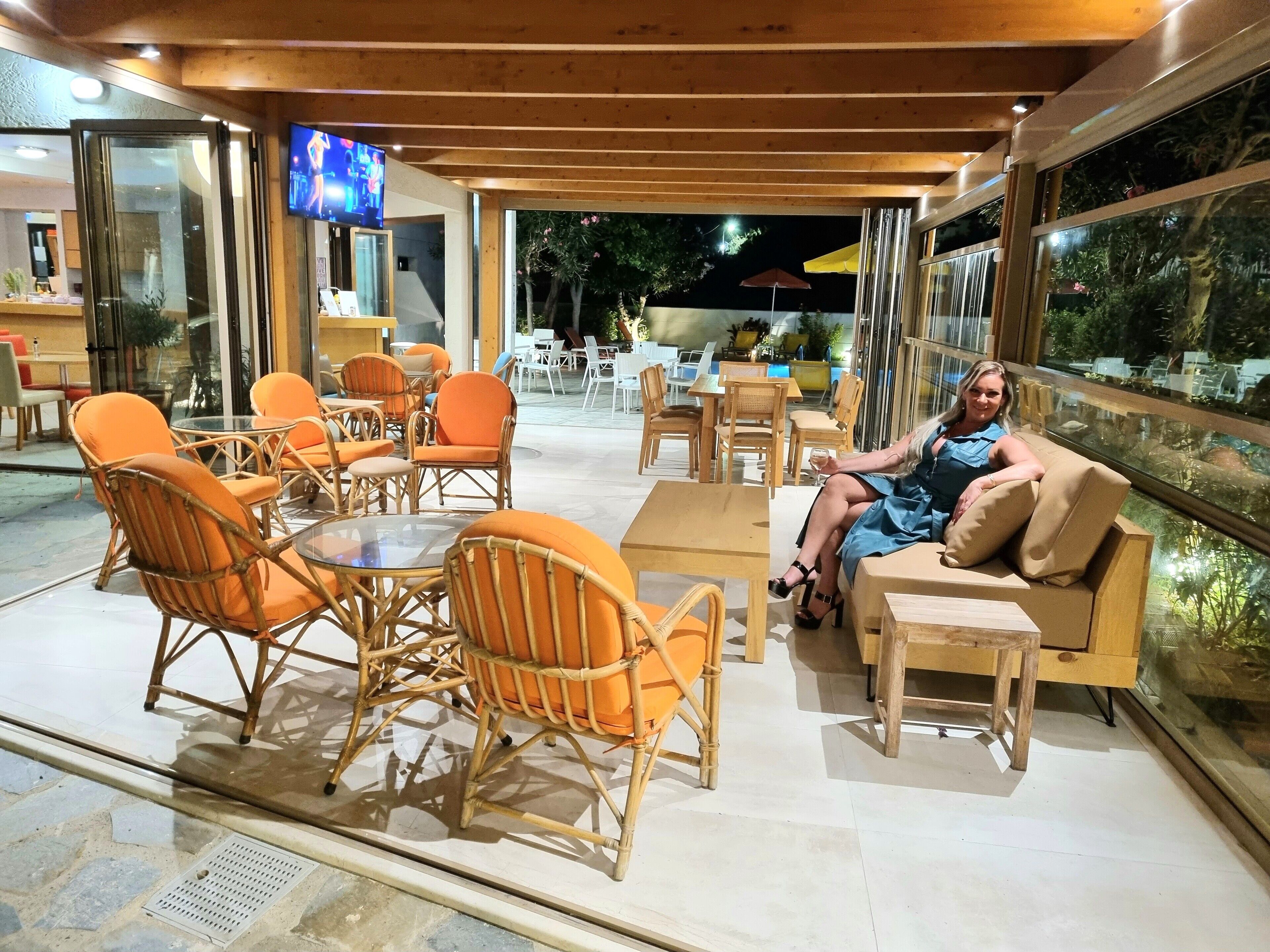 An outdoor seating area with wicker chairs and tables, a television screen, and a view of the night sky.