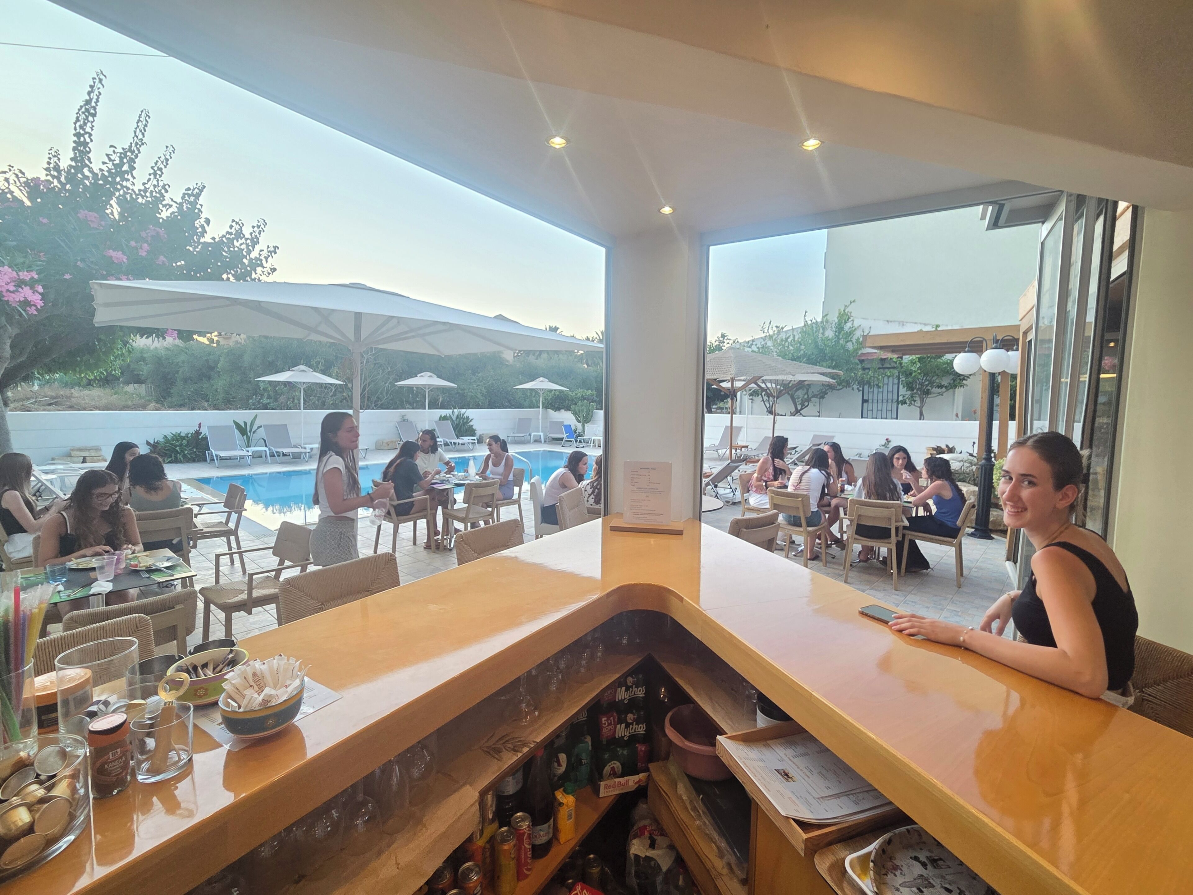 Un espace bar avec vue sur la piscine, comprenant des tables et des chaises.