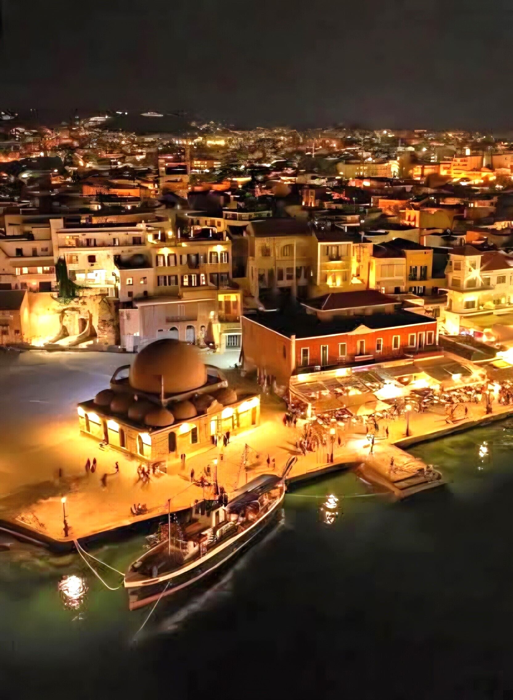 An aerial view of a waterfront area with buildings, a dock, and a boat.