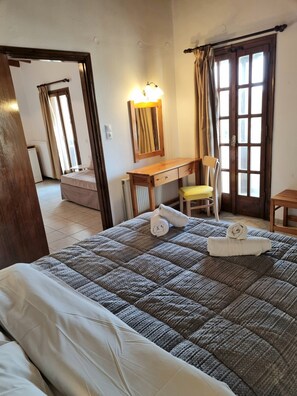 A hotel room with a bed, a desk, a chair, and a window with curtains.