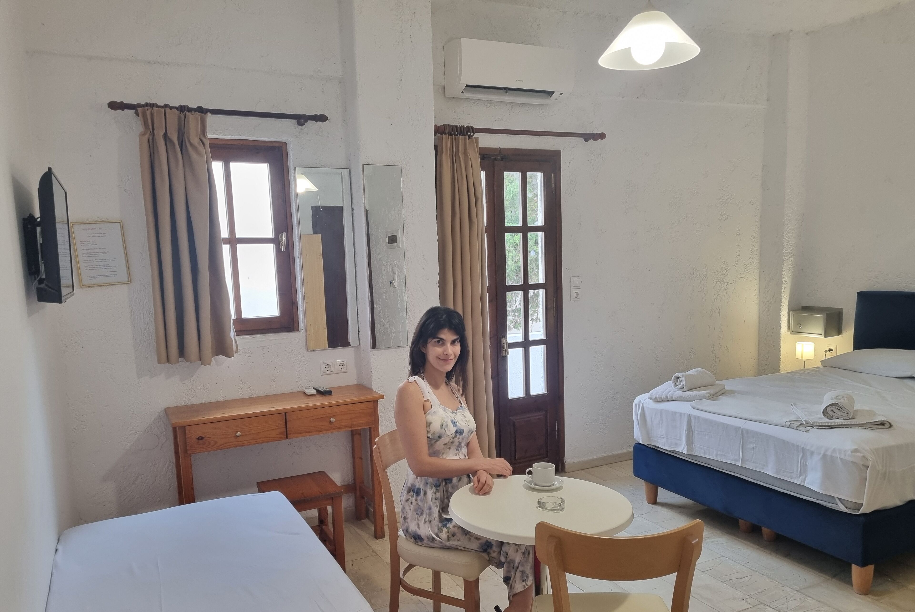 A hotel room with a bed, a desk, a chair, a round table, and a window with curtains.