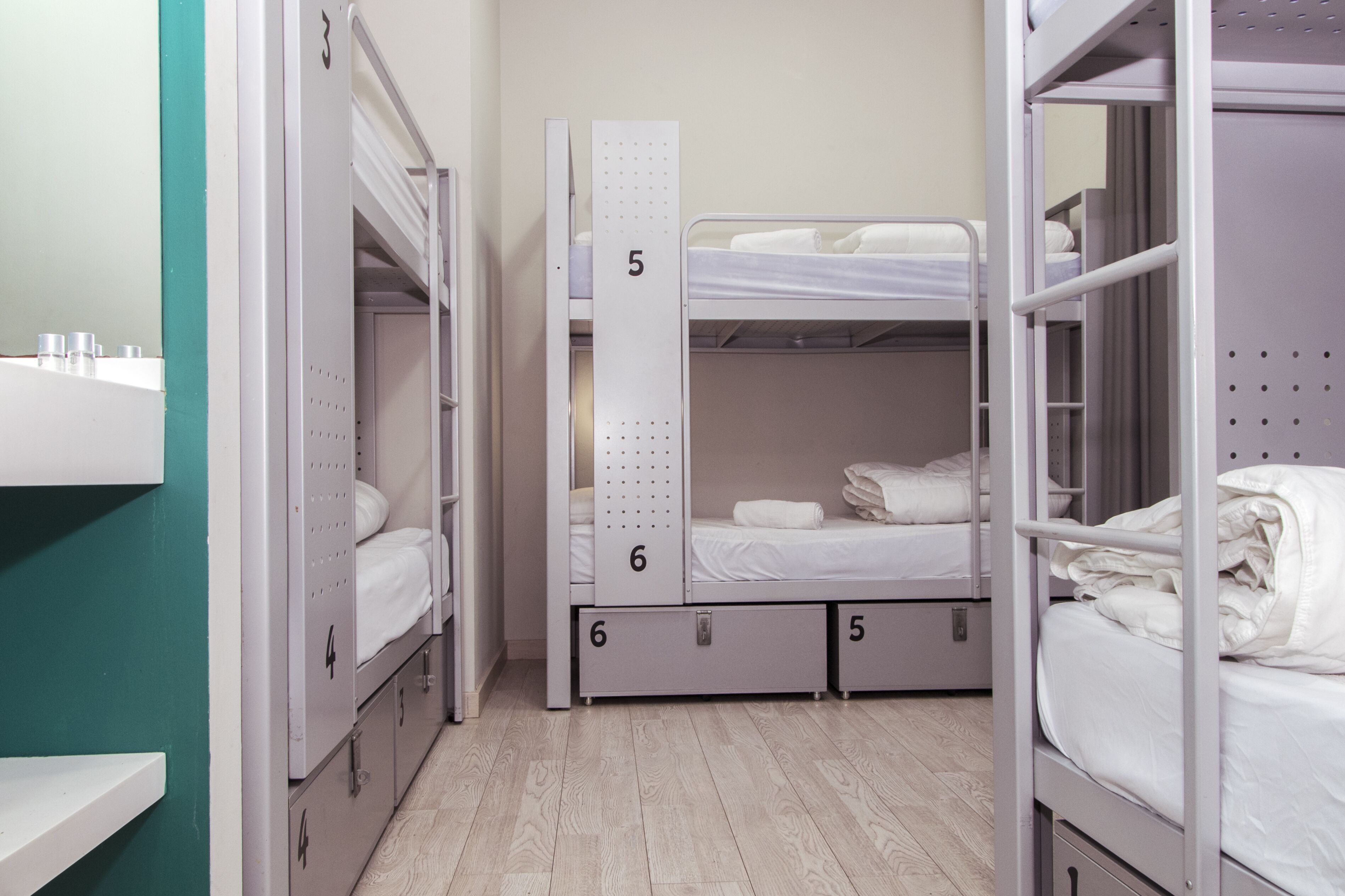 A dormitory room with bunk beds, numbered storage units, and a wooden floor.