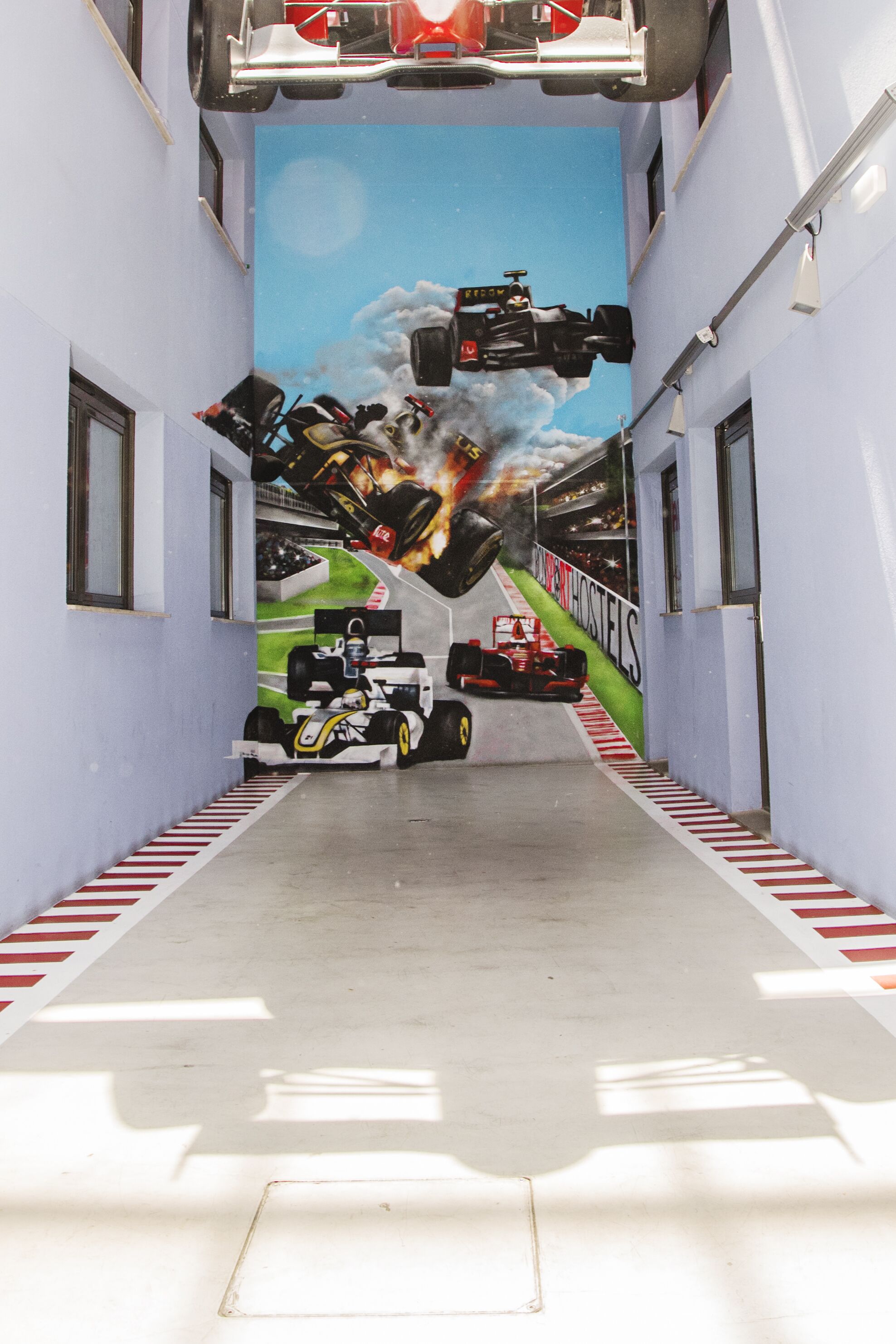 Un pasillo decorado con un mural de coches de carreras y un área de boxes.