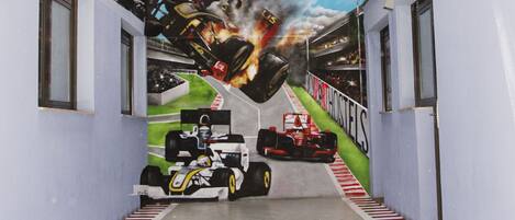 A hallway with a mural of racing cars and a pit stop.