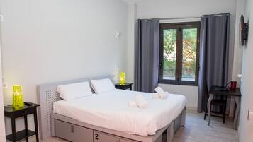 A bedroom with a bed, bedside tables, a desk, and a window with curtains.