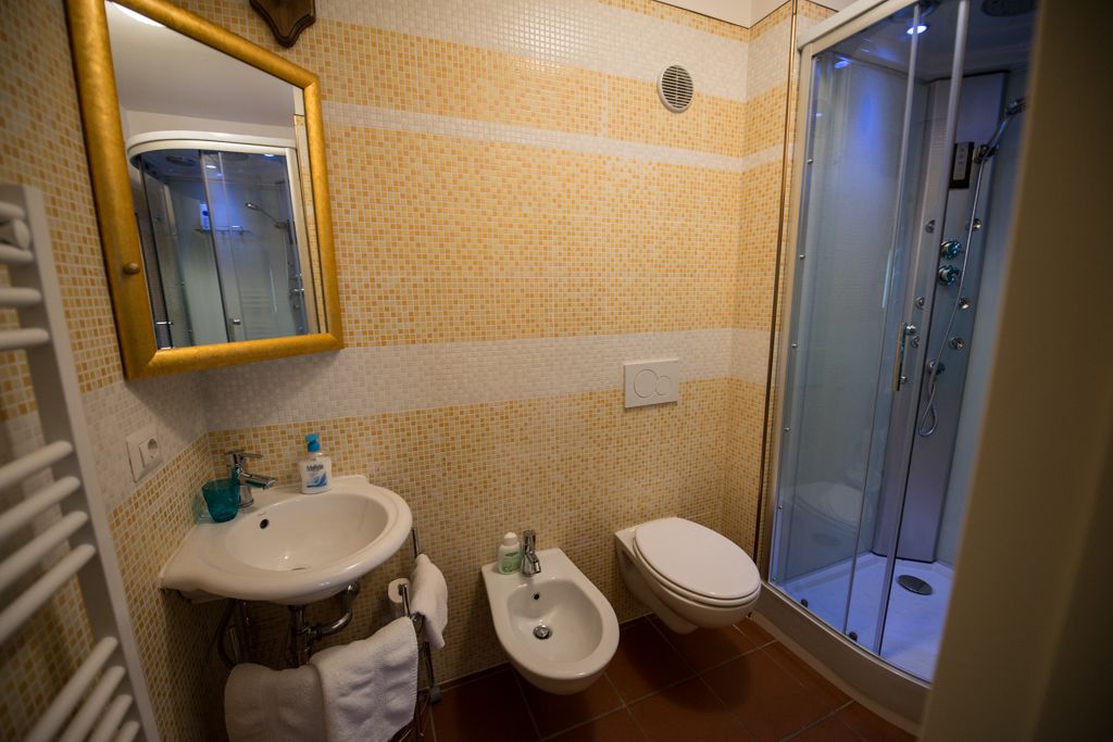 A bathroom with a sink, bidet, toilet, and a glass-enclosed shower.