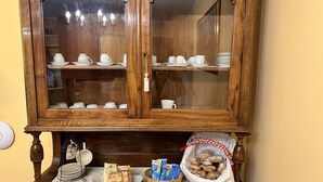Een houten kast met glazen deuren, daarin witte serviesgoed, en een tafel met eten en een mand.