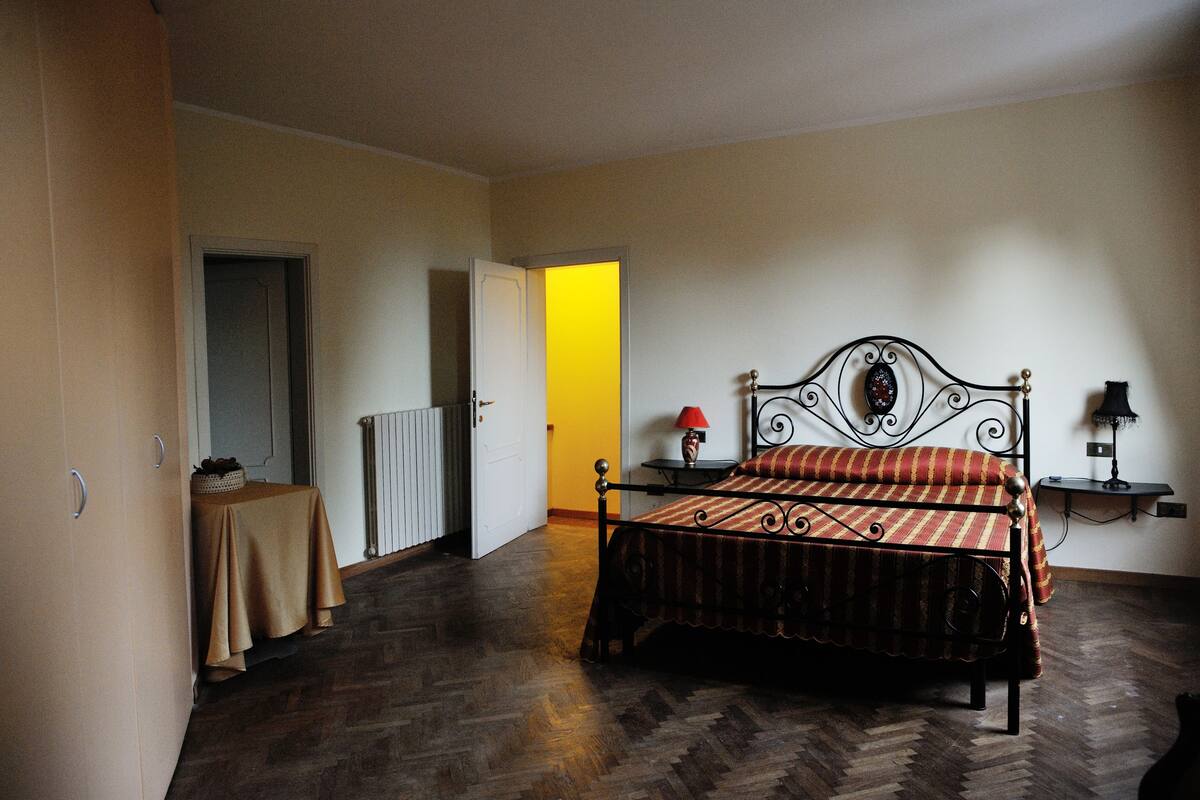A bedroom with a bed, a table, a lamp, and a radiator.