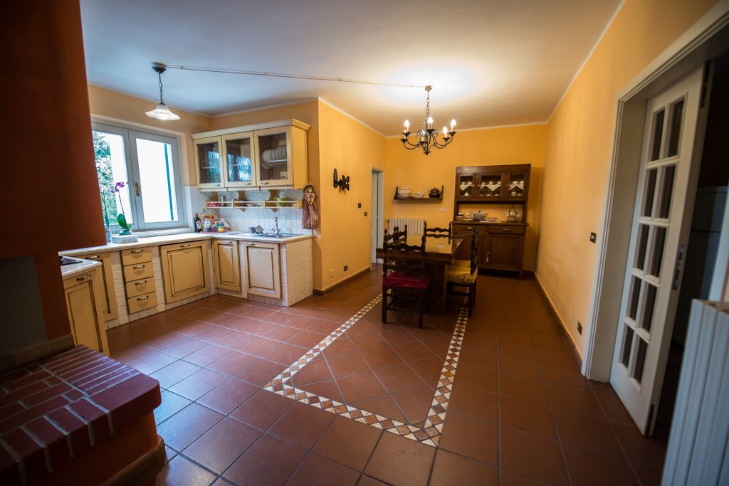 A kitchen with white cabinets, a dining area with a red chair, and a patterned floor.