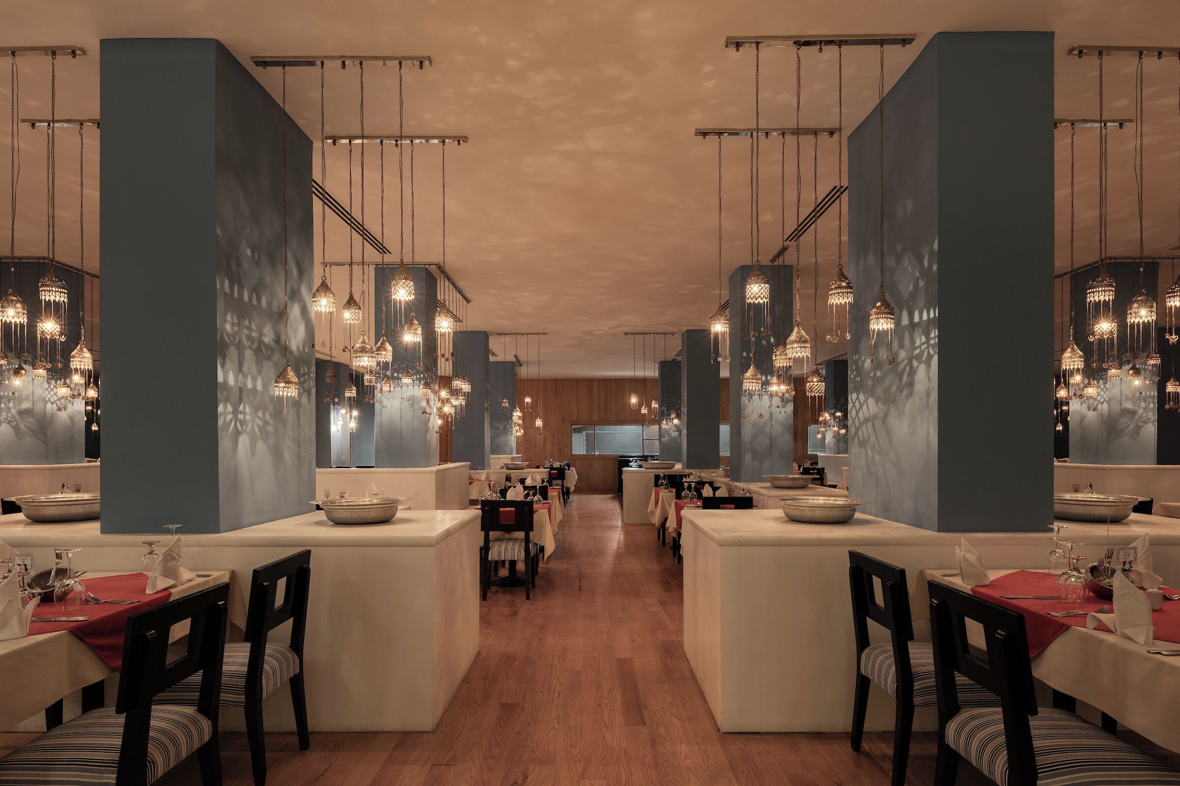 A restaurant with multiple dining tables, hanging crystal chandeliers, and a central counter.