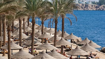 Praia particular, areia branca, espreguiçadeiras, guarda-sóis