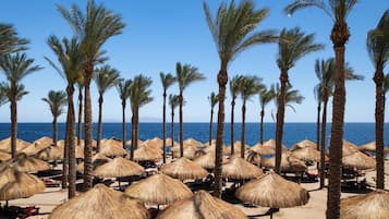 Privat strand, hvit sand, solsenger og parasoller