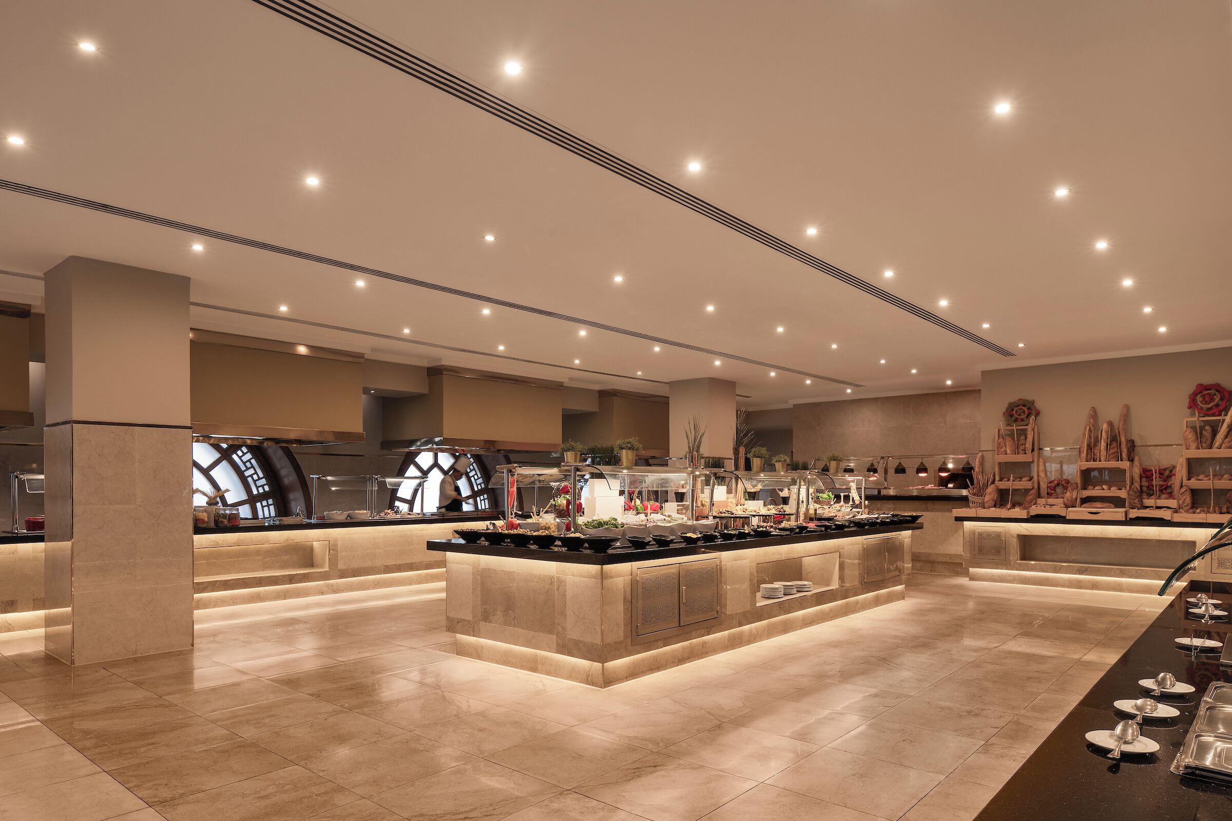A spacious hotel lobby with a central island, a large window, and a reception desk.