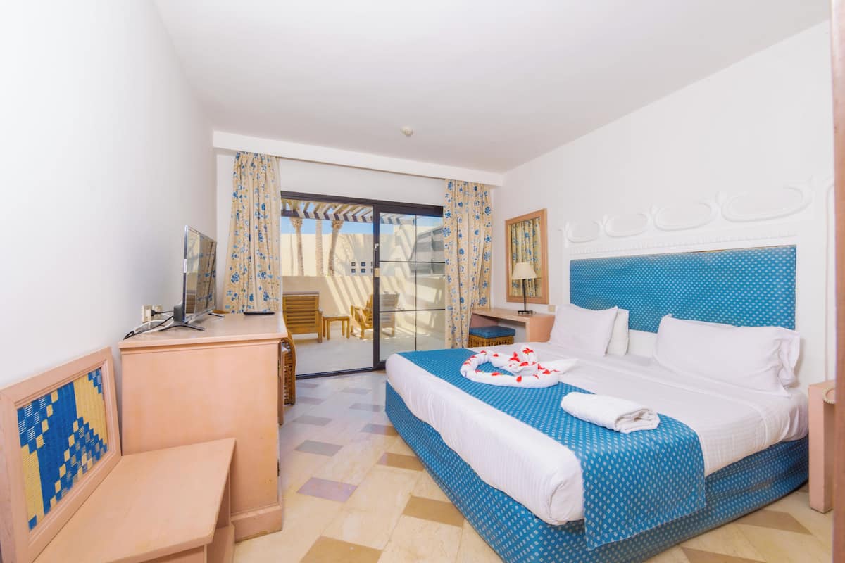 Une chambre d’hôtel équipée d’un lit, d’un bureau, d’une chaise, d’un miroir et offrant une vue sur l’extérieur.