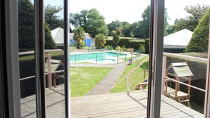 A view from a balcony overlooking a swimming pool, garden, and a white tent. - Hotel Voar (Ribadeo)