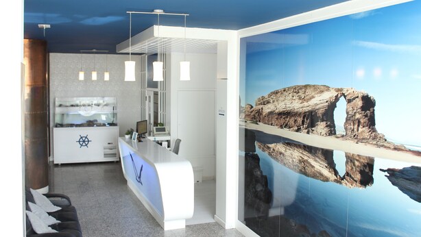 A modern reception area with a counter, seating, and a large rock formation mural. - Hotel Voar (Ribadeo)