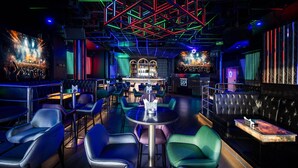 A modern bar with neon lighting, leather seating, and a bar area with a counter and shelves. - TRYP by Wyndham Abu Dhabi City Centre (Abu Dhabi)