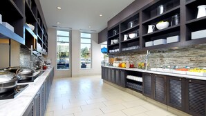 Een moderne keuken met een centraal eiland, inbouwplanken en een groot raam.