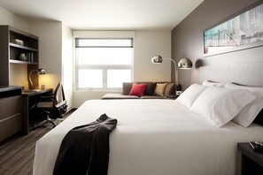 A hotel room with a large bed, a desk, a chair, a bookshelf, and a window. - Hyatt House Pittsburgh/Bloomfield/Shadyside (Pittsburgh)