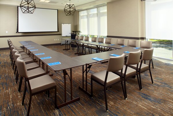 A conference room with a long table, chairs, a projector screen, and a whiteboard. - Hyatt House Pittsburgh/Bloomfield/Shadyside (Pittsburgh)