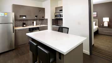 Uma cozinha moderna com uma ilha central, eletrodomésticos de aço inoxidável e uma área de jantar com banquetas.