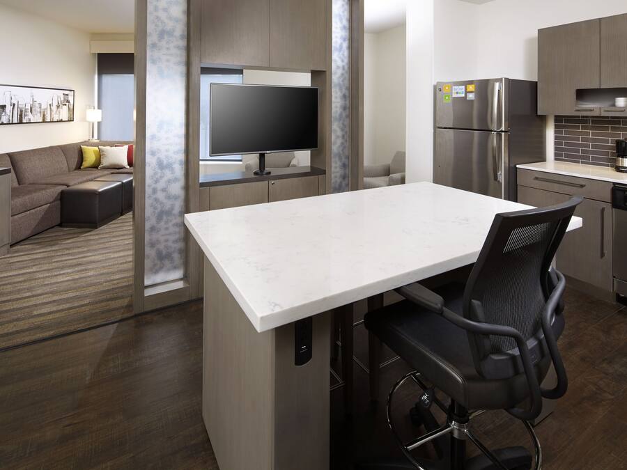 A modern kitchen with a built-in refrigerator, a flat-screen TV, and a coffee maker.