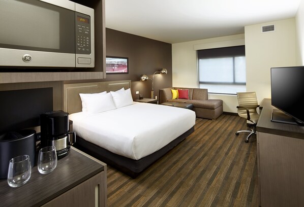 A hotel room with a bed, a desk with a computer, a microwave, a coffee maker, and a TV. - Hyatt House Pittsburgh/Bloomfield/Shadyside (Pittsburgh)