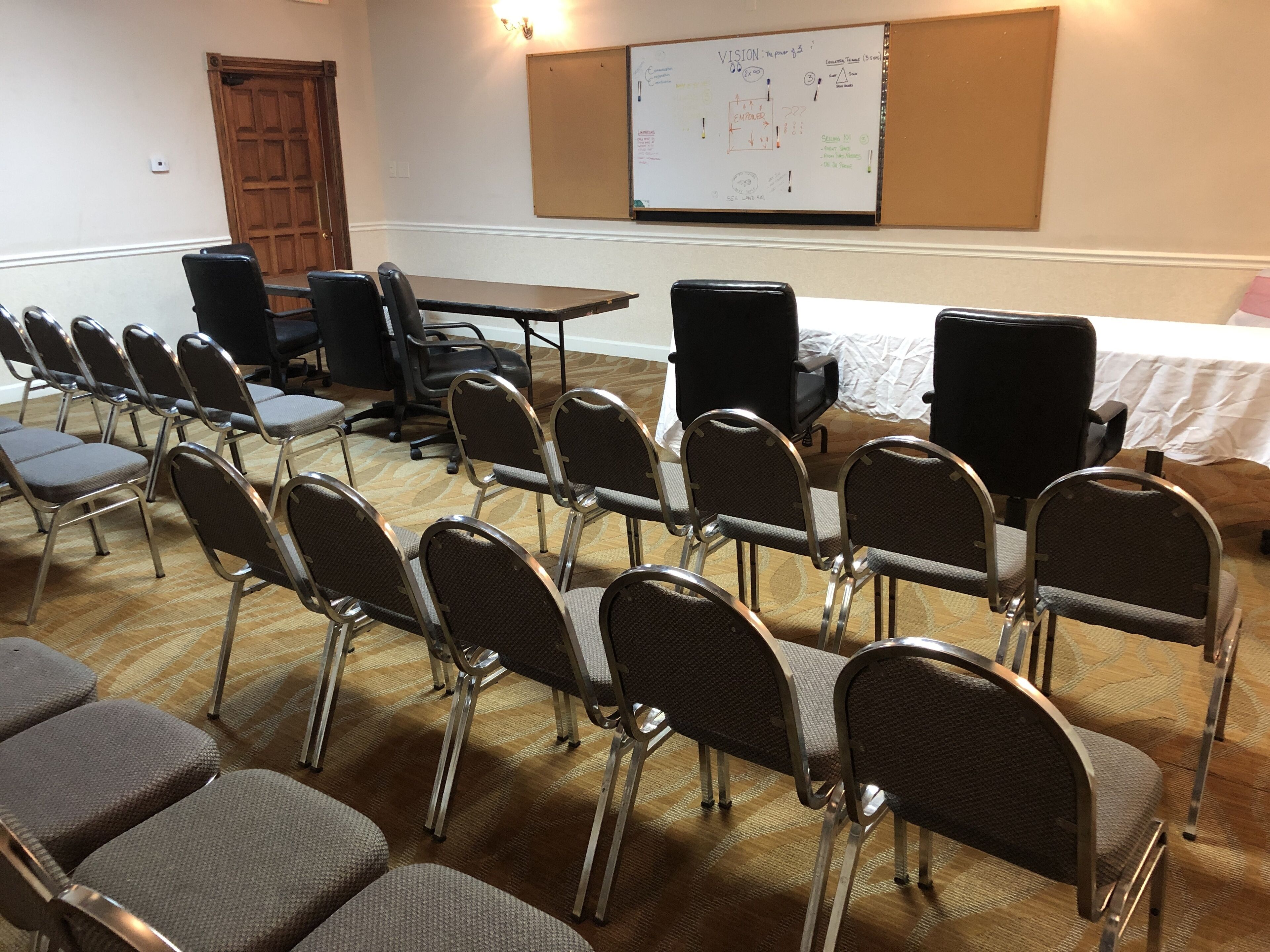 A conference room with rows of chairs, a table, and a whiteboard with diagrams.