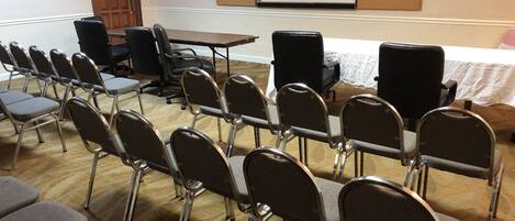 A conference room with rows of chairs, a table, and a whiteboard with diagrams.