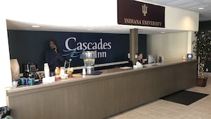 En receptionsdisk på Indiana University med et skilt for 'Cascades Inn' og en kaffemaskine.