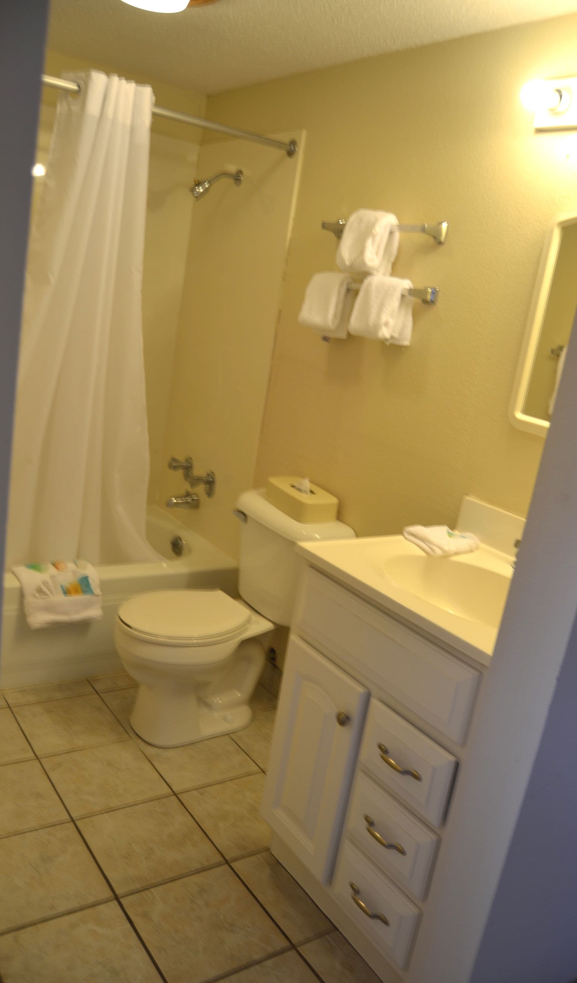 A bathroom with a shower, toilet, sink, and a towel rack.