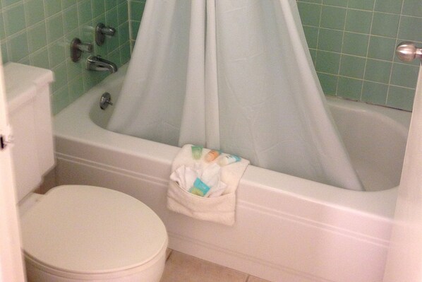 A bathroom with a white bathtub, a toilet, and a shower curtain.
