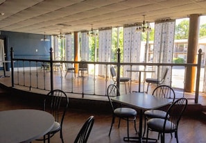 Enjoy meals with a view from the dining area, featuring tables and chairs, a balcony, and a grid-patterned ceiling.