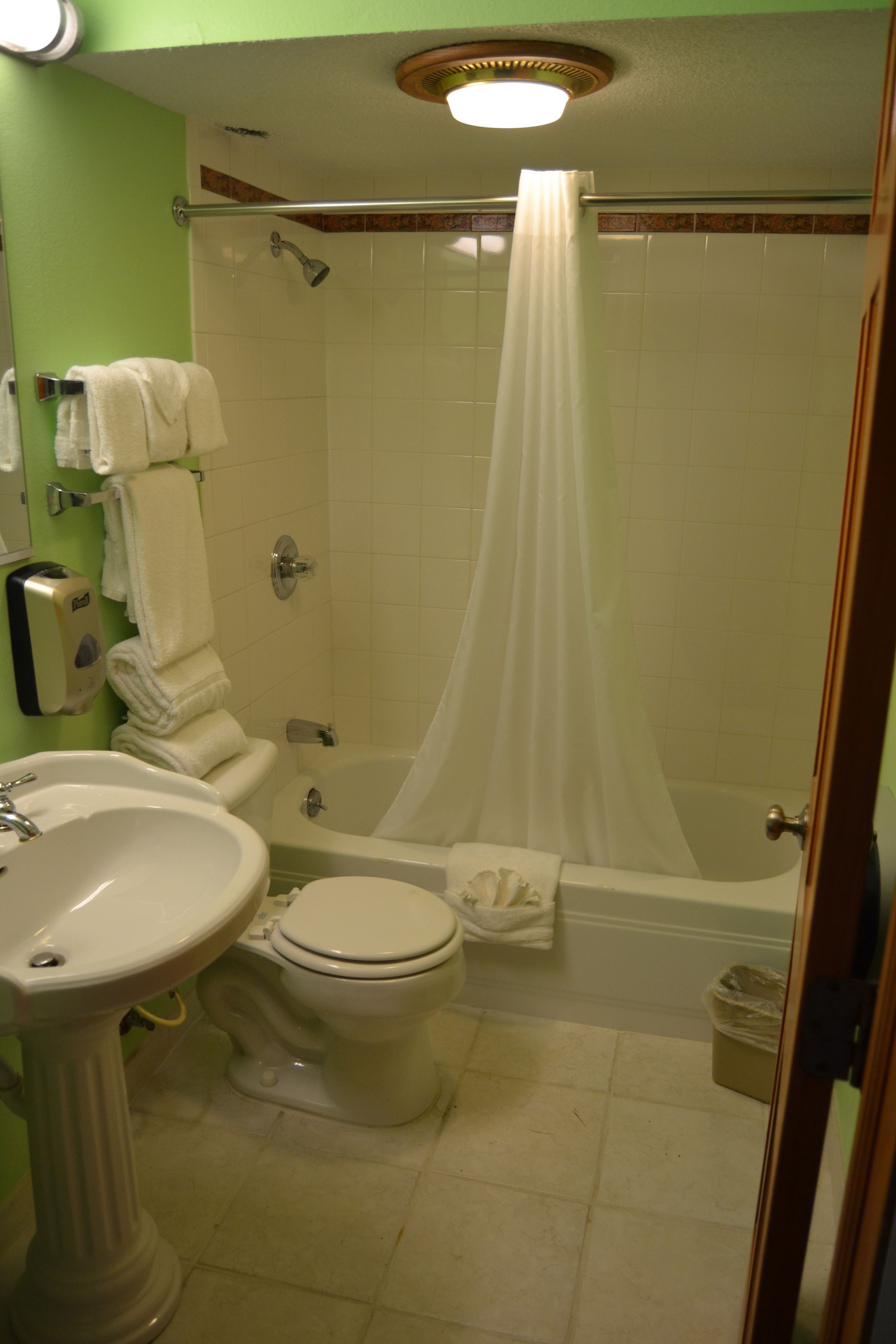 A bathroom with a toilet, sink, shower, and a curtain.