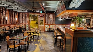 En restaurantindretning med flere borde og stole, et barområde og udsigt udad.