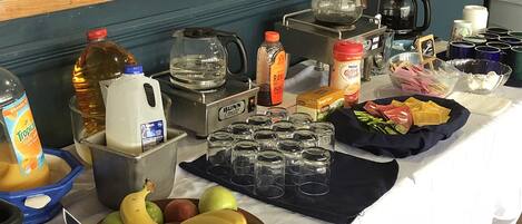 A table with various food items, a coffee maker, and a Bunn coffee grinder.