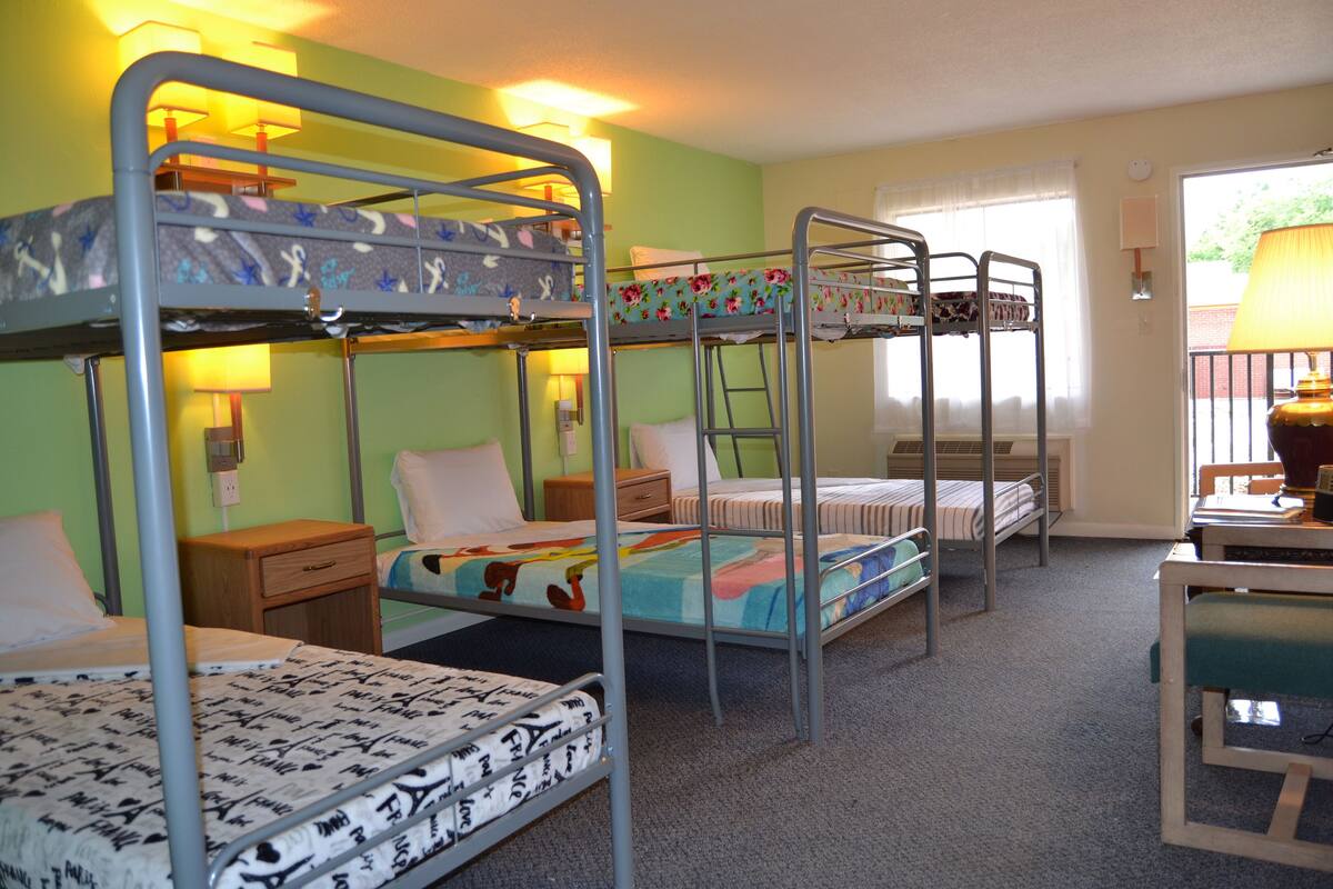 A room with bunk beds, a desk, and a lamp.