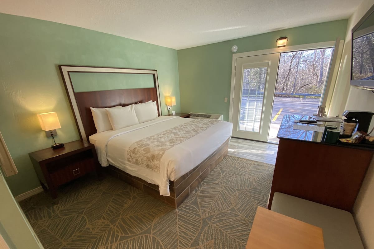 A neatly made bed with a headboard, bedside lamps, and a patterned rug.