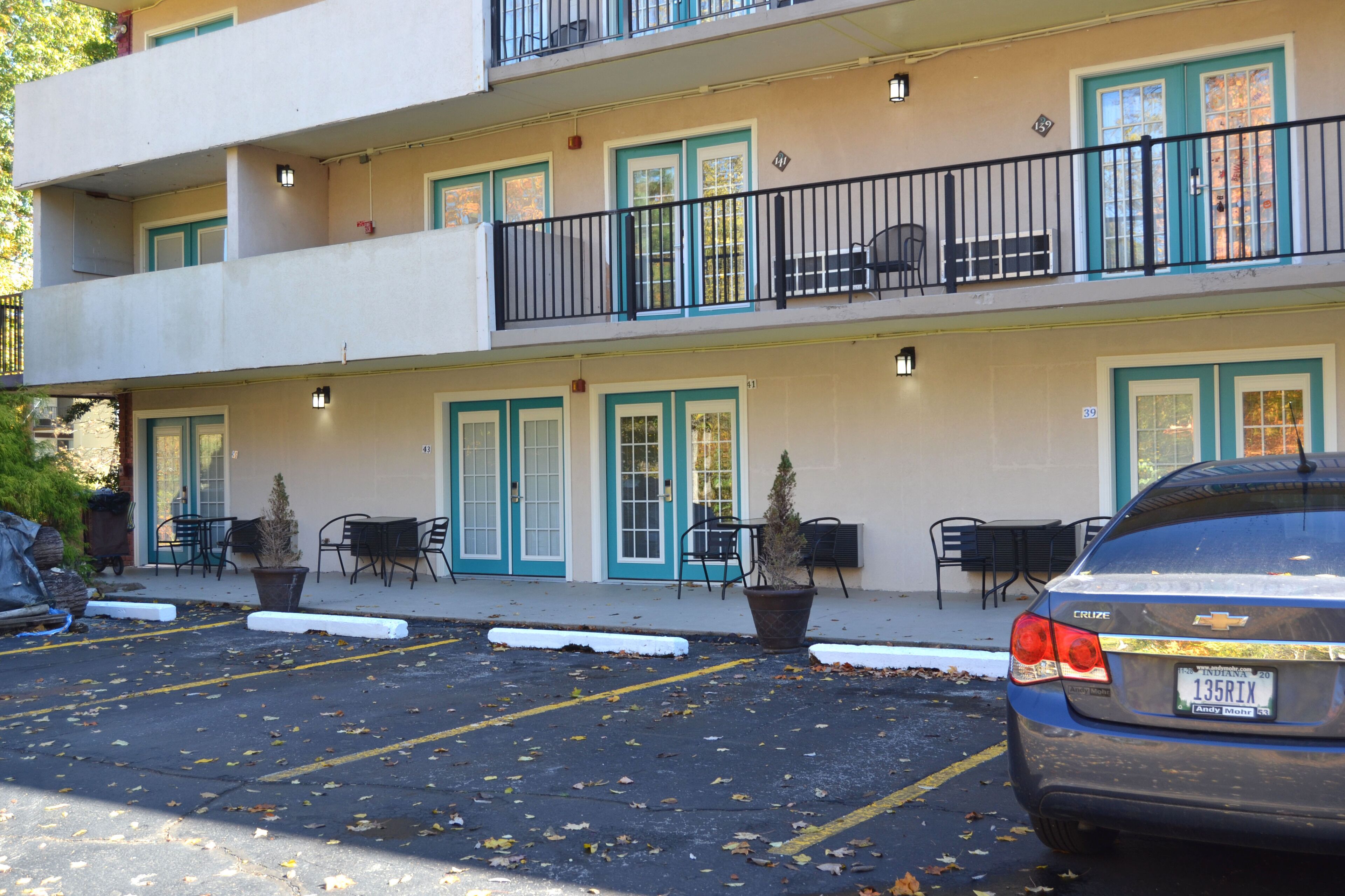 A multi-story hotel with outdoor seating and a parking area.