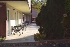 Rows of hotel rooms line the sidewalk, each with a door and light fixture above.