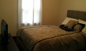 A hotel room with a bed, a television, and a window with curtains. - Del Mar -Youngstown (Warren)